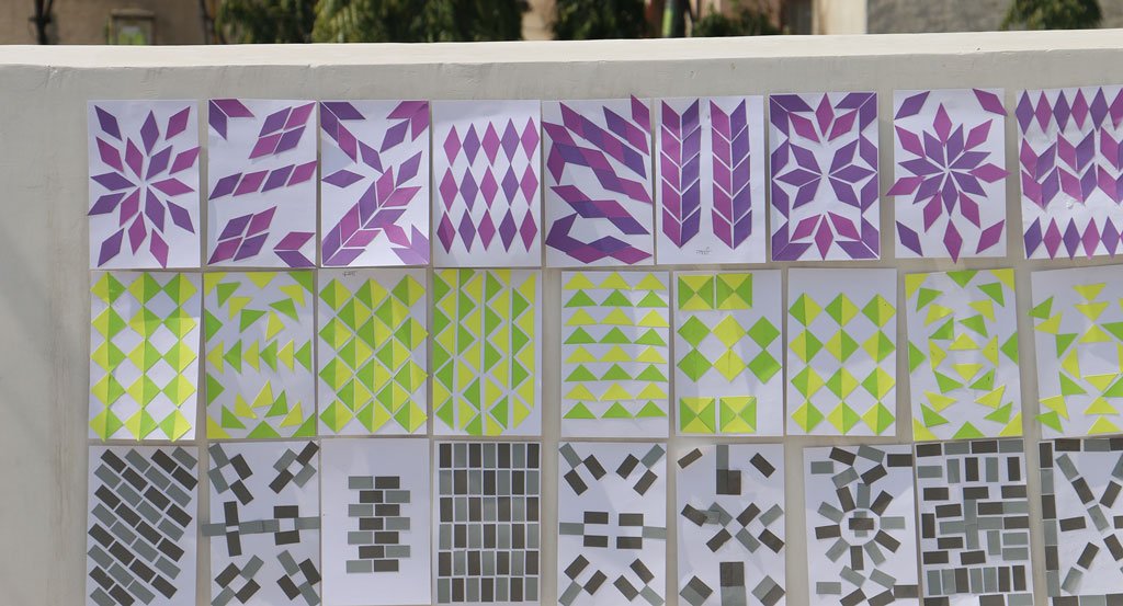 Twenty-seven sheets of unique patterned artwork categorized into three rows of color, purple, yellow and green, and black and grey