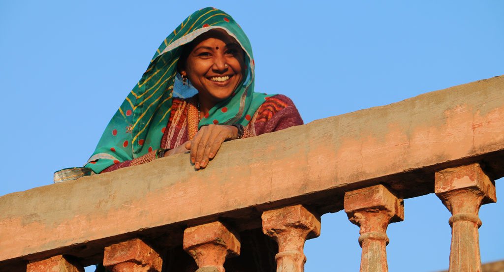 Young artisan woman leaning and smiling over a balcony