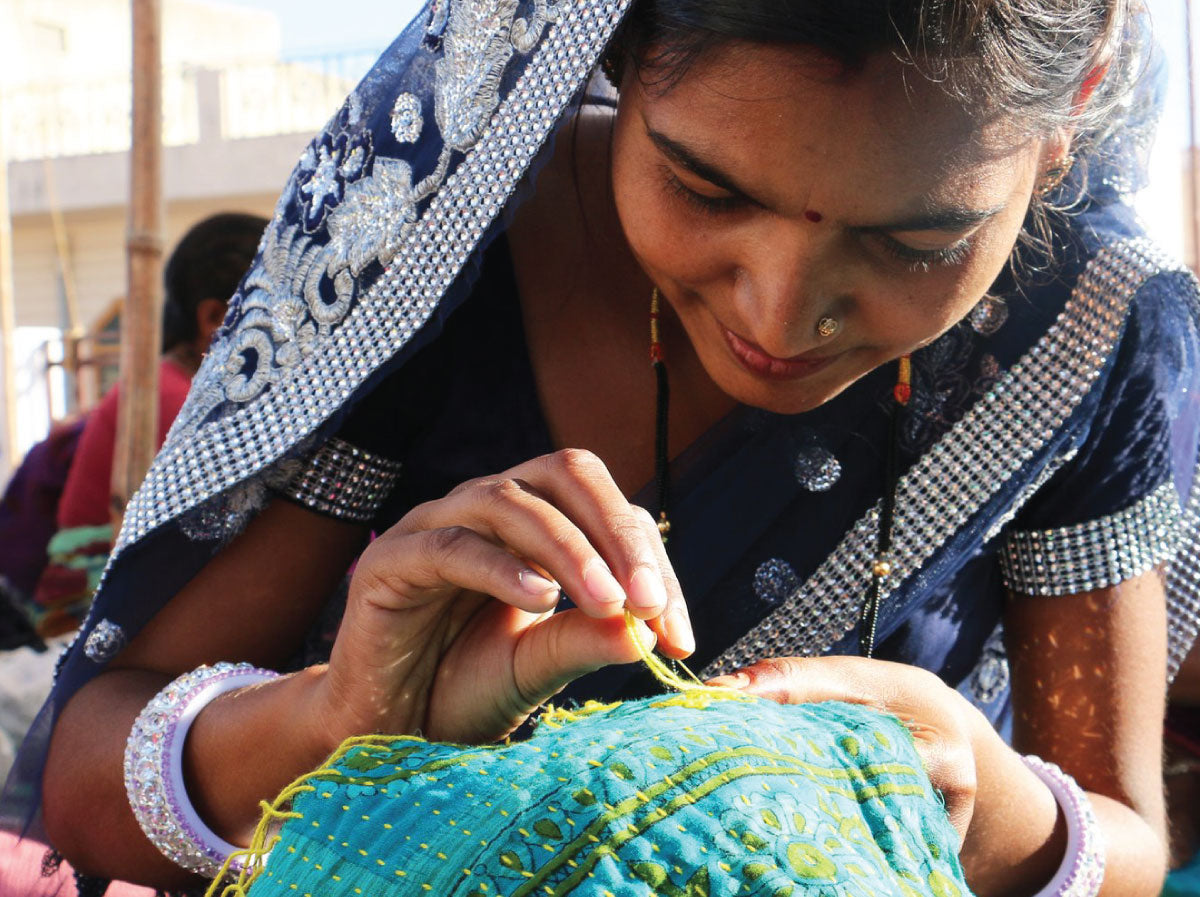 Anchal artisan sewing an intricate pattern into a teal fabric