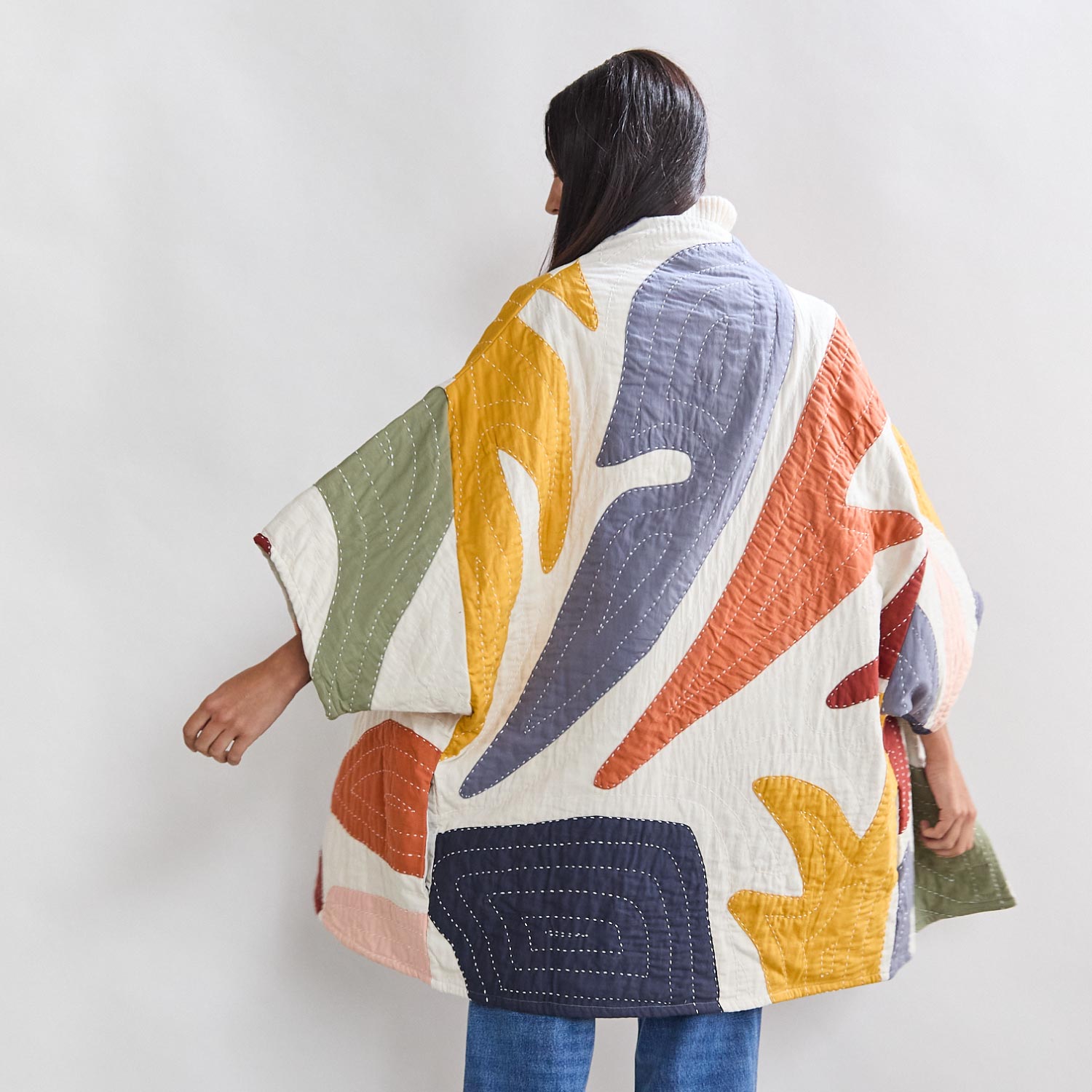 woman wearing organic cotton quilted jacket with colorful abstract shapes handmade in India