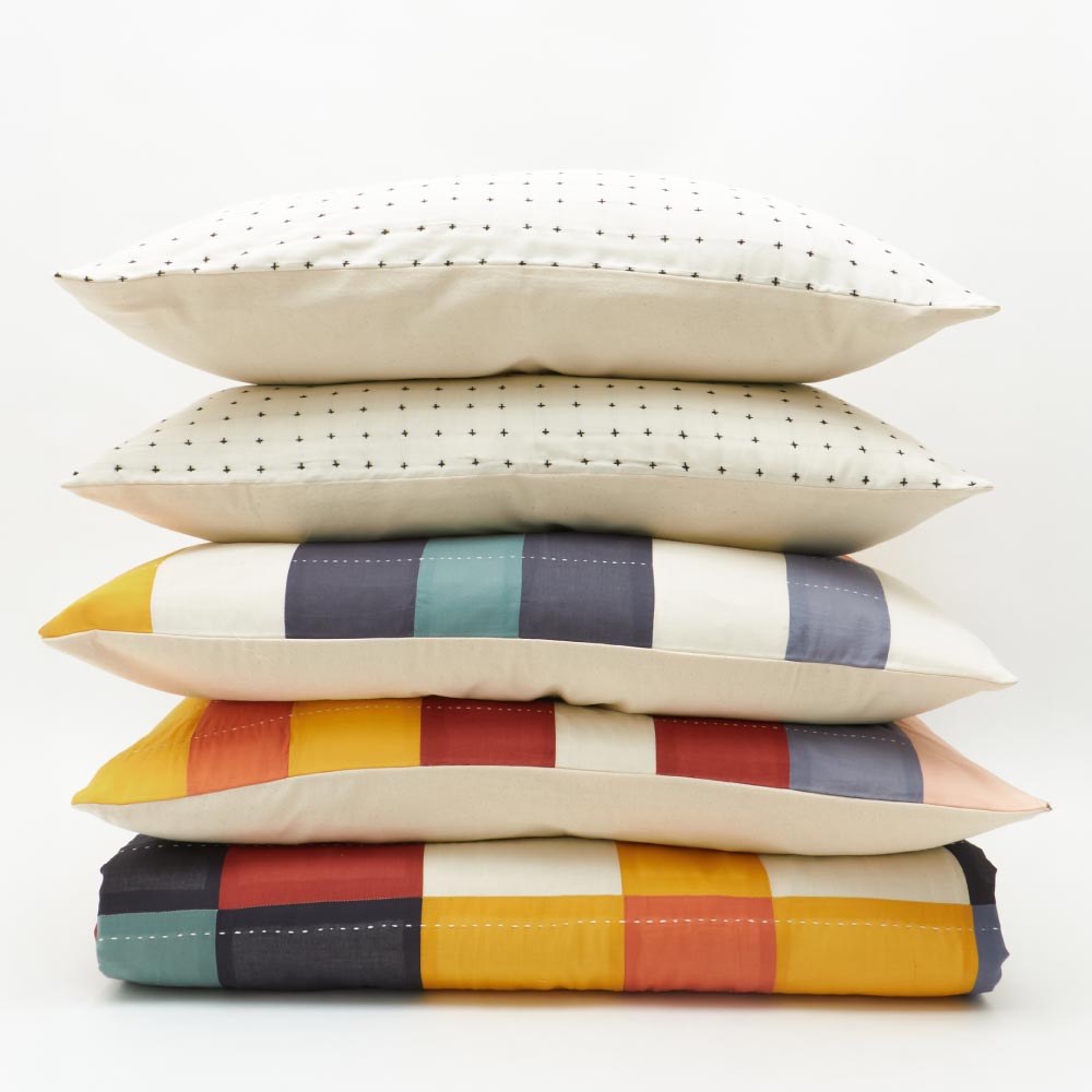 stack of pillows and quilts in a rainbow of colors
