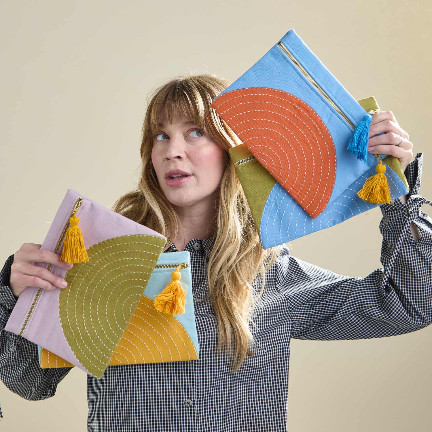 woman holding different colored pouches with a half moon circular design