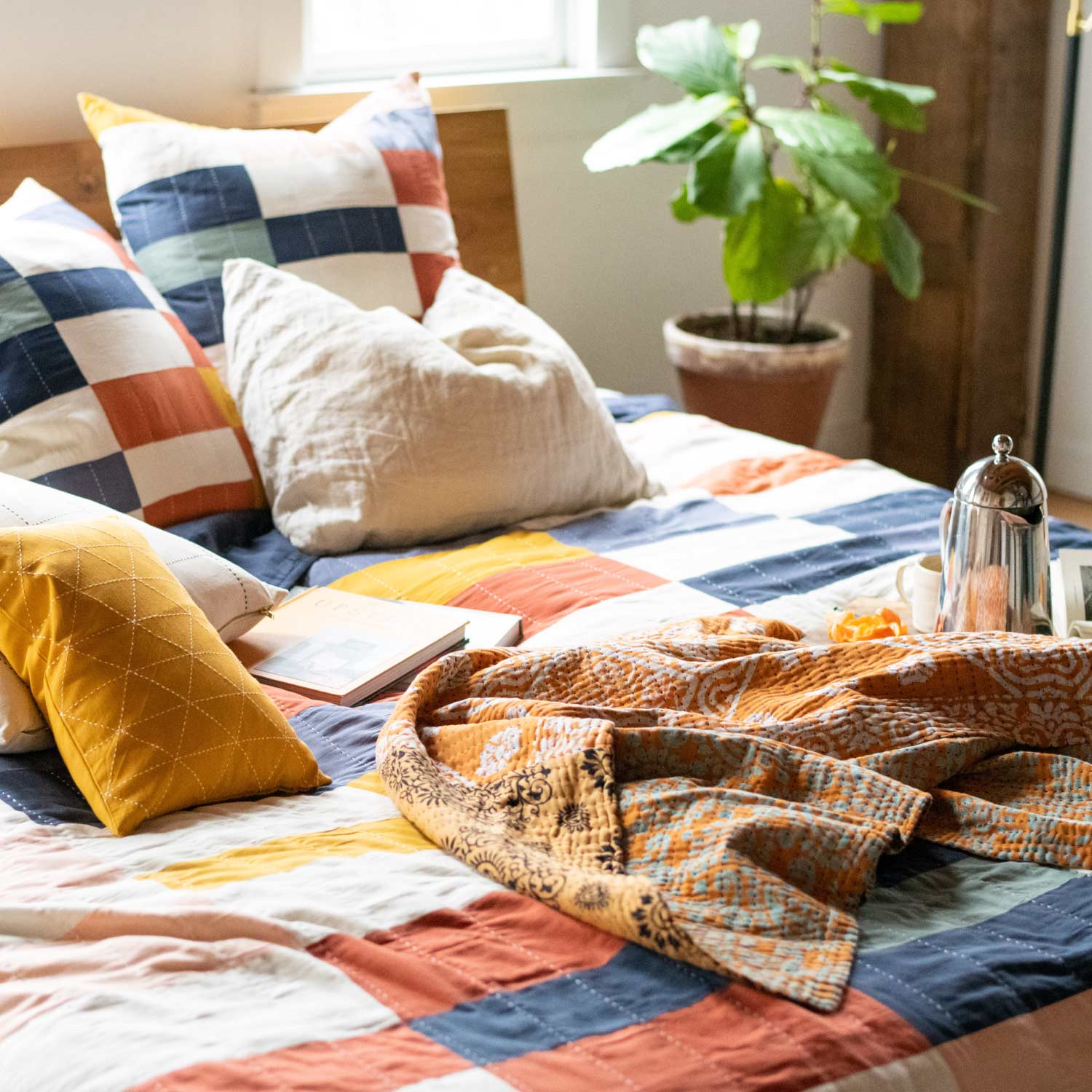 colorful checkered patchwork quilt with matching throw pillows and kantha quilt