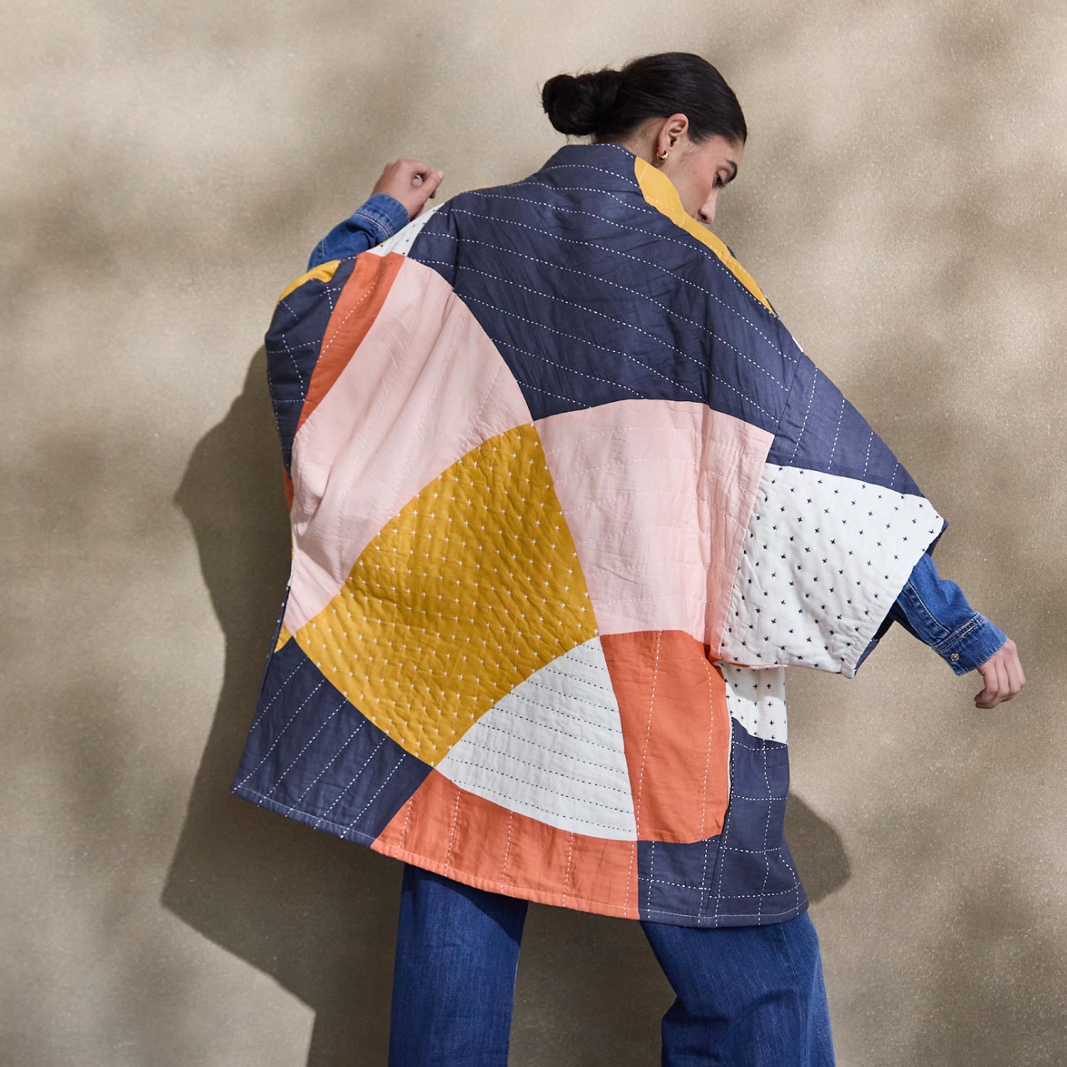 woman wearing modern patchwork jacket with abstract shapes in navy blue, yellow, pink, orange & white
