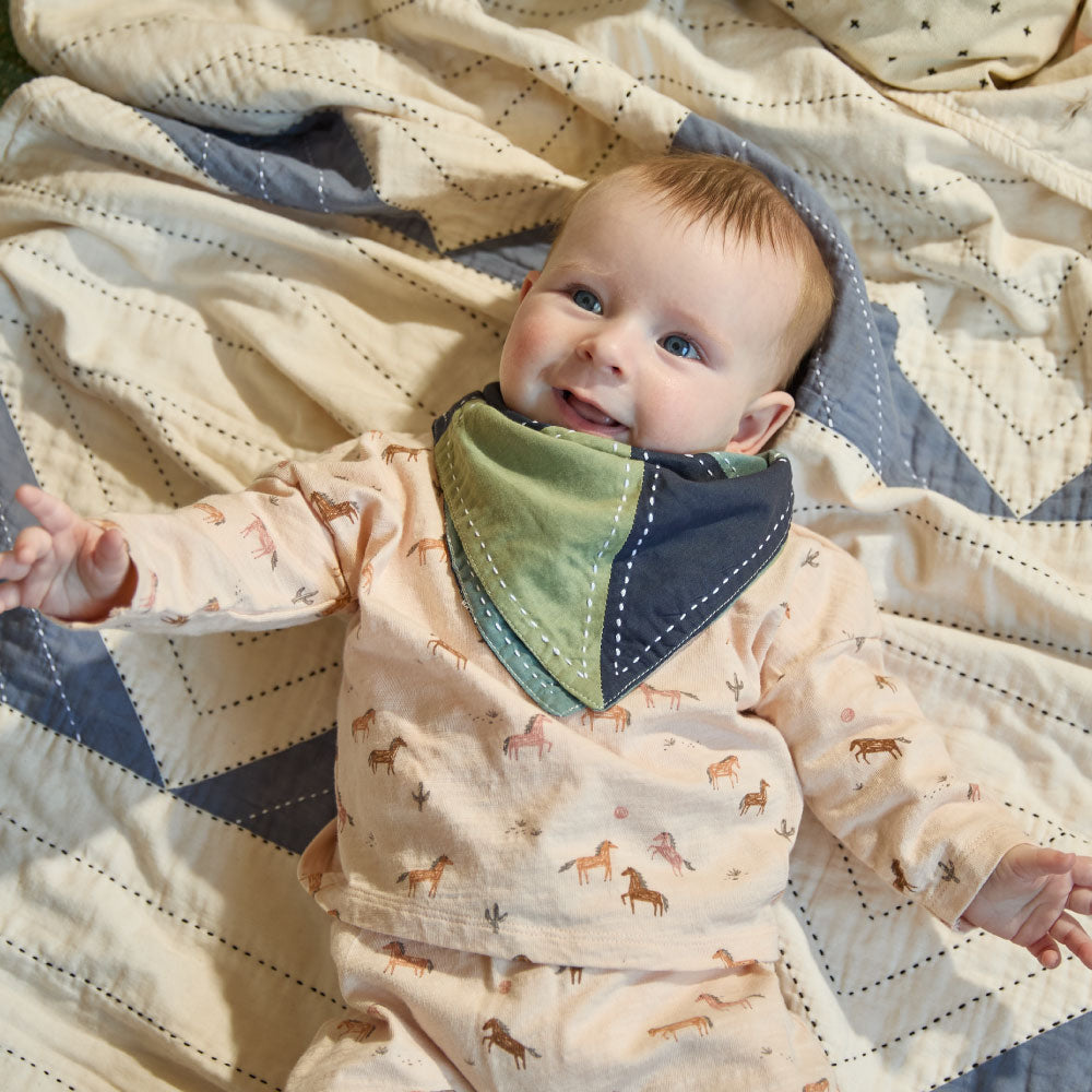 baby girl wearing bandana bib in sage green and navy colorblock pattern