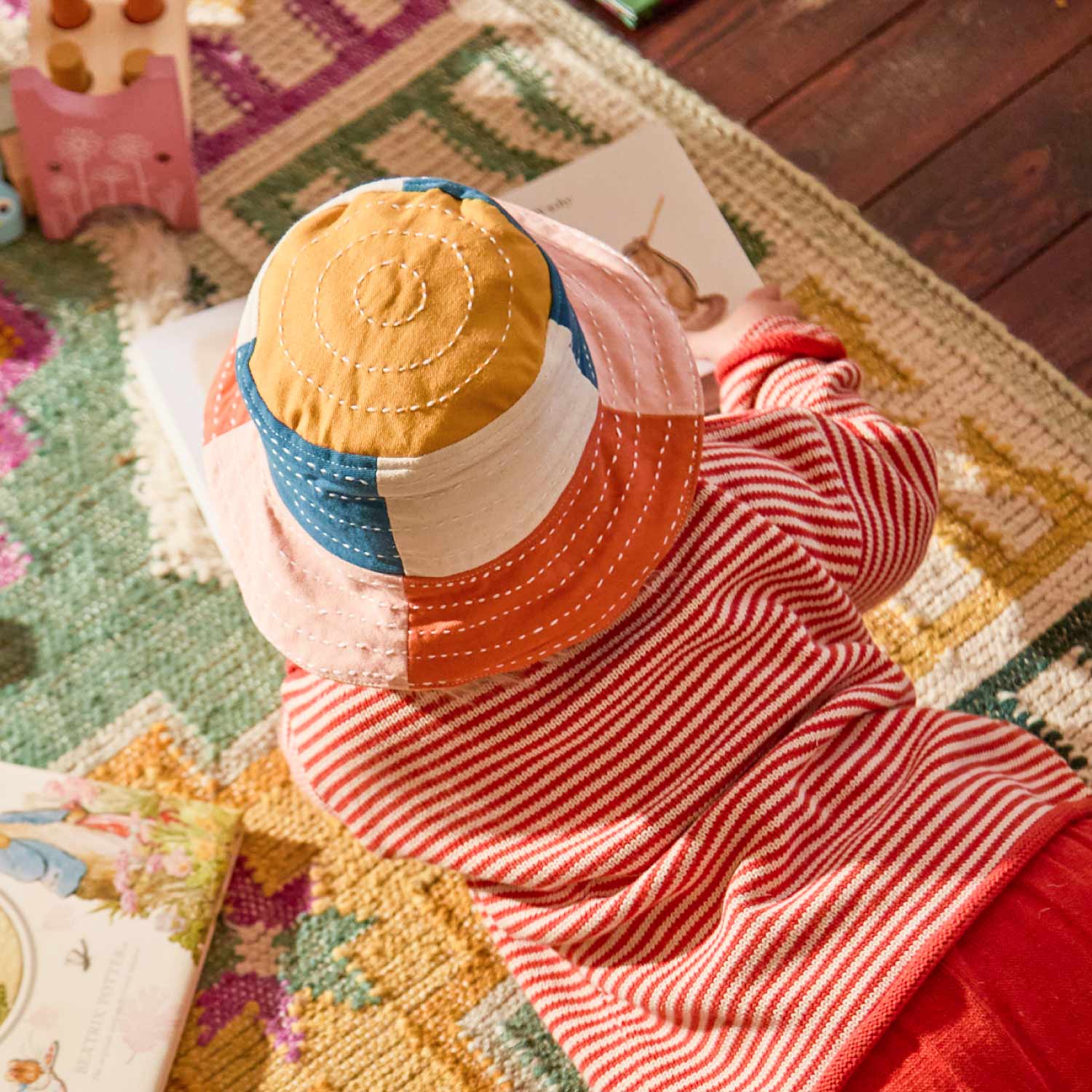 toddler wearing colorblock bucket hat in shades of cobalt blue, mustard yellow, pink and orange