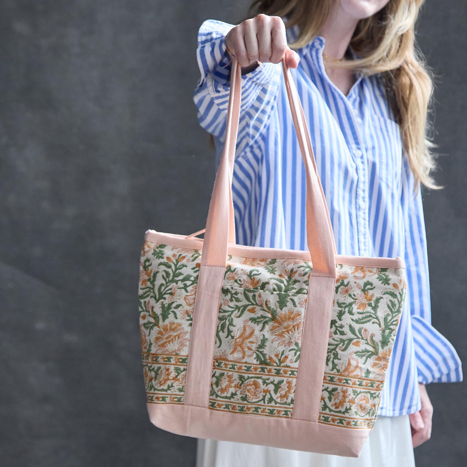 woman holding block print floral mini tote bag in pink