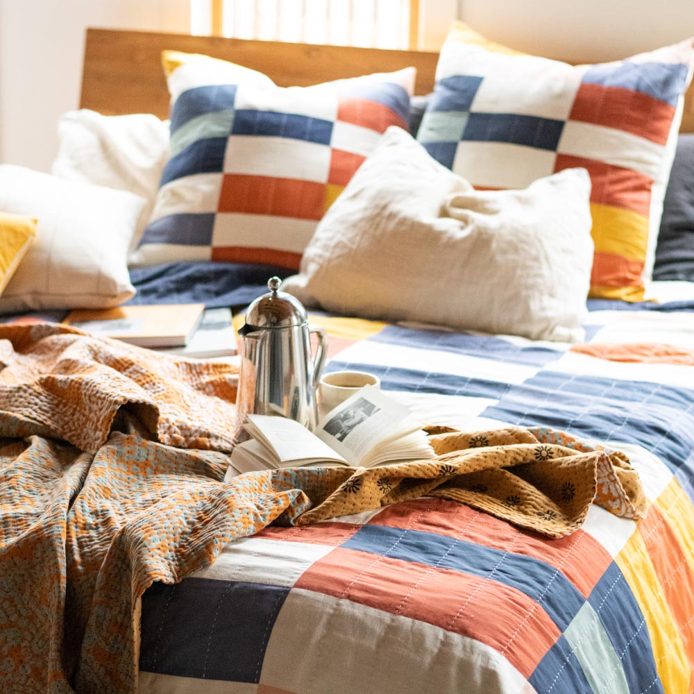 colorful checkered bedding on queen size bed with natural wooden headboard