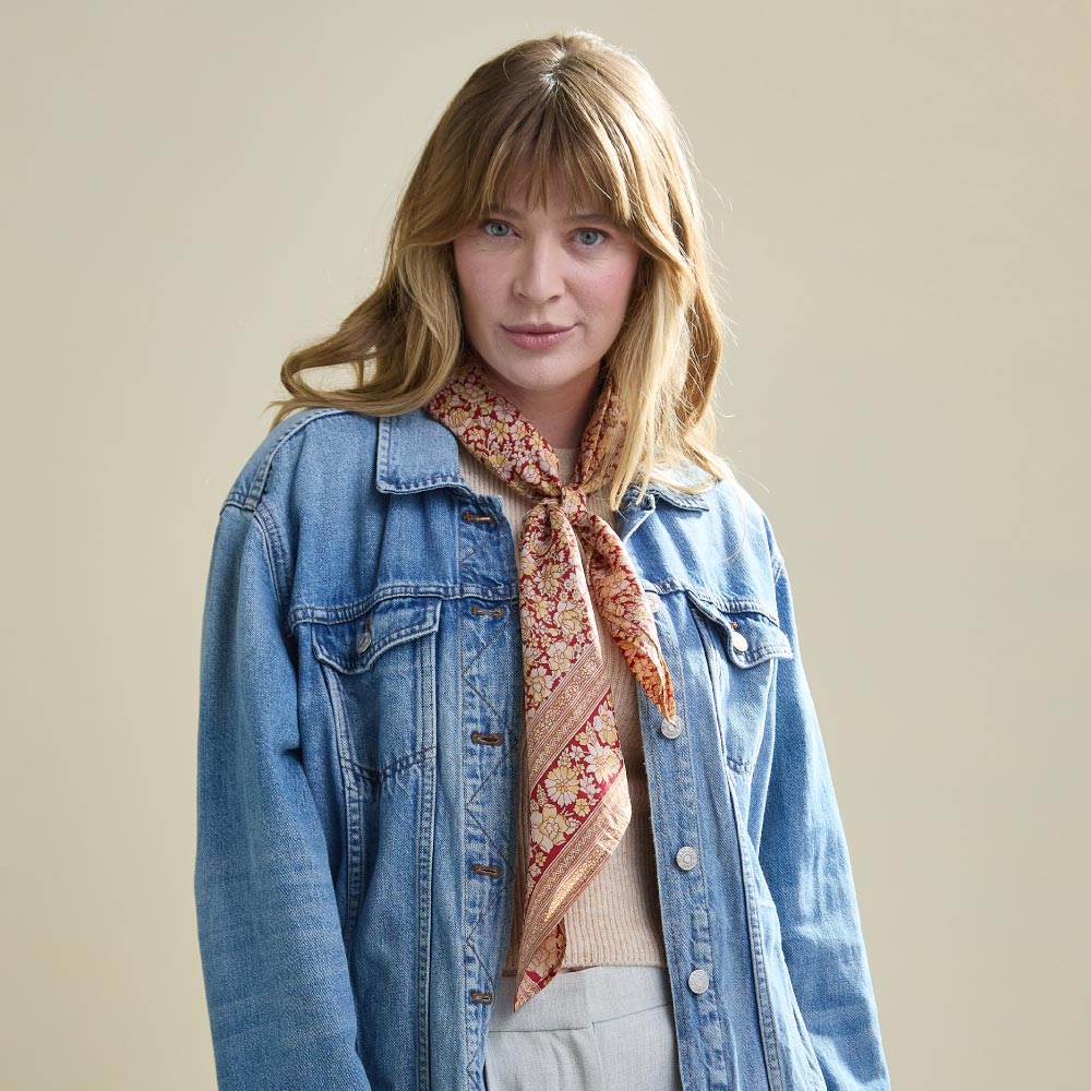 woman wearing rolled up silk square scarf around neck with a denim jacket
