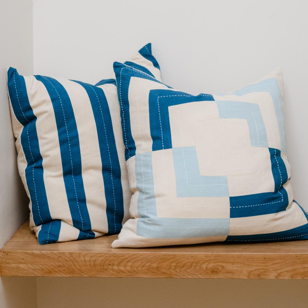 cobaly blue and cloud blue geometric stripe throw pillows on light wooden entry way bench
