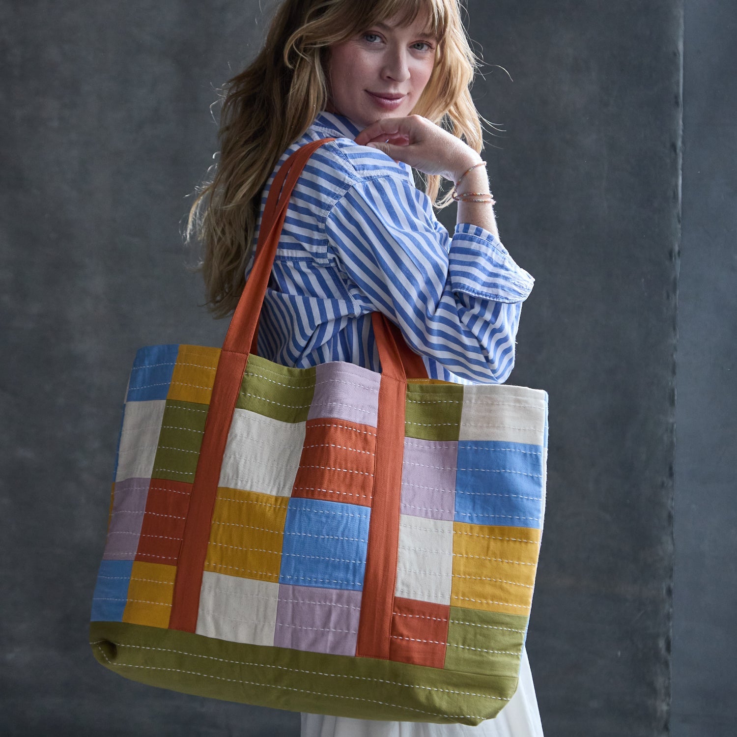 woman wearing colorful orange, green, yellow, lilac, and blue checkered tote bag in canvas