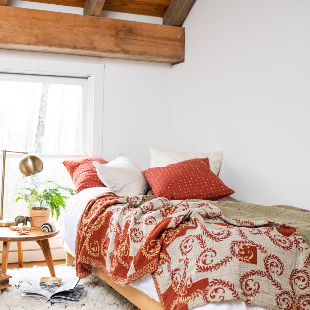 twin kantha quilt on twin bed with wooden nightstand and brass bedside lamp