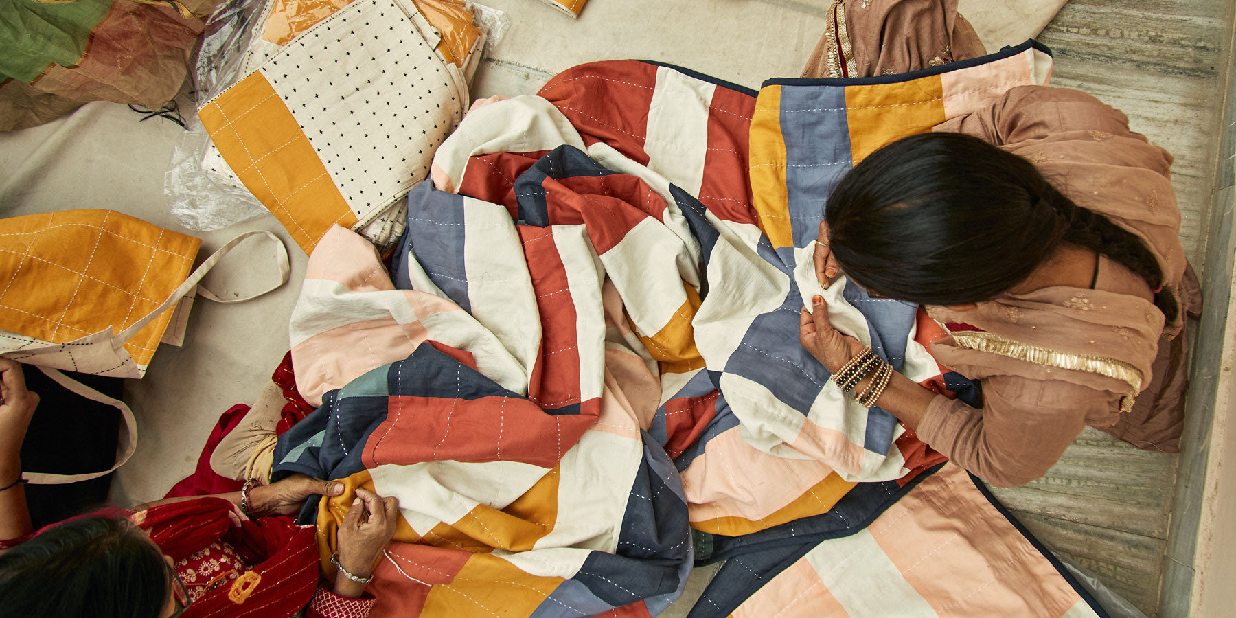 woman artisan in Ajmer, India hand-embroidering a colorful checkered quilt in Anchal's workshop