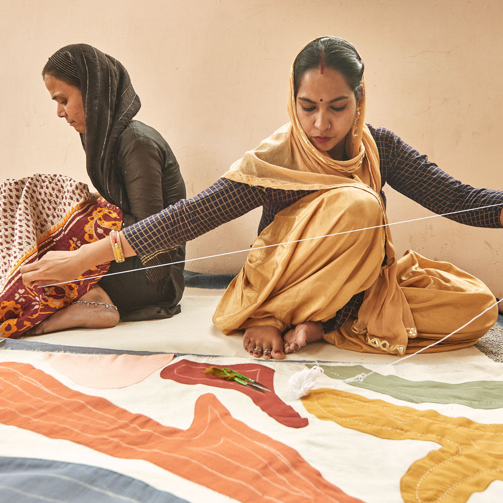 woman measuring white thread with petal quilt in front of her to hand-embroider