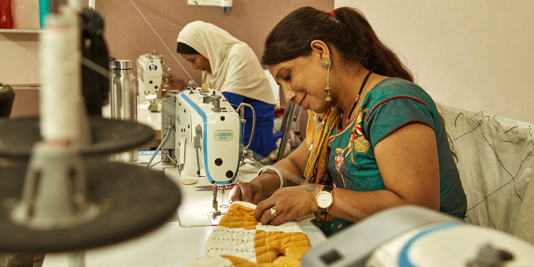 woman artisan using industrial sewing machine to sew a organic cotton potholder in Anchal's Ajmer, India studio