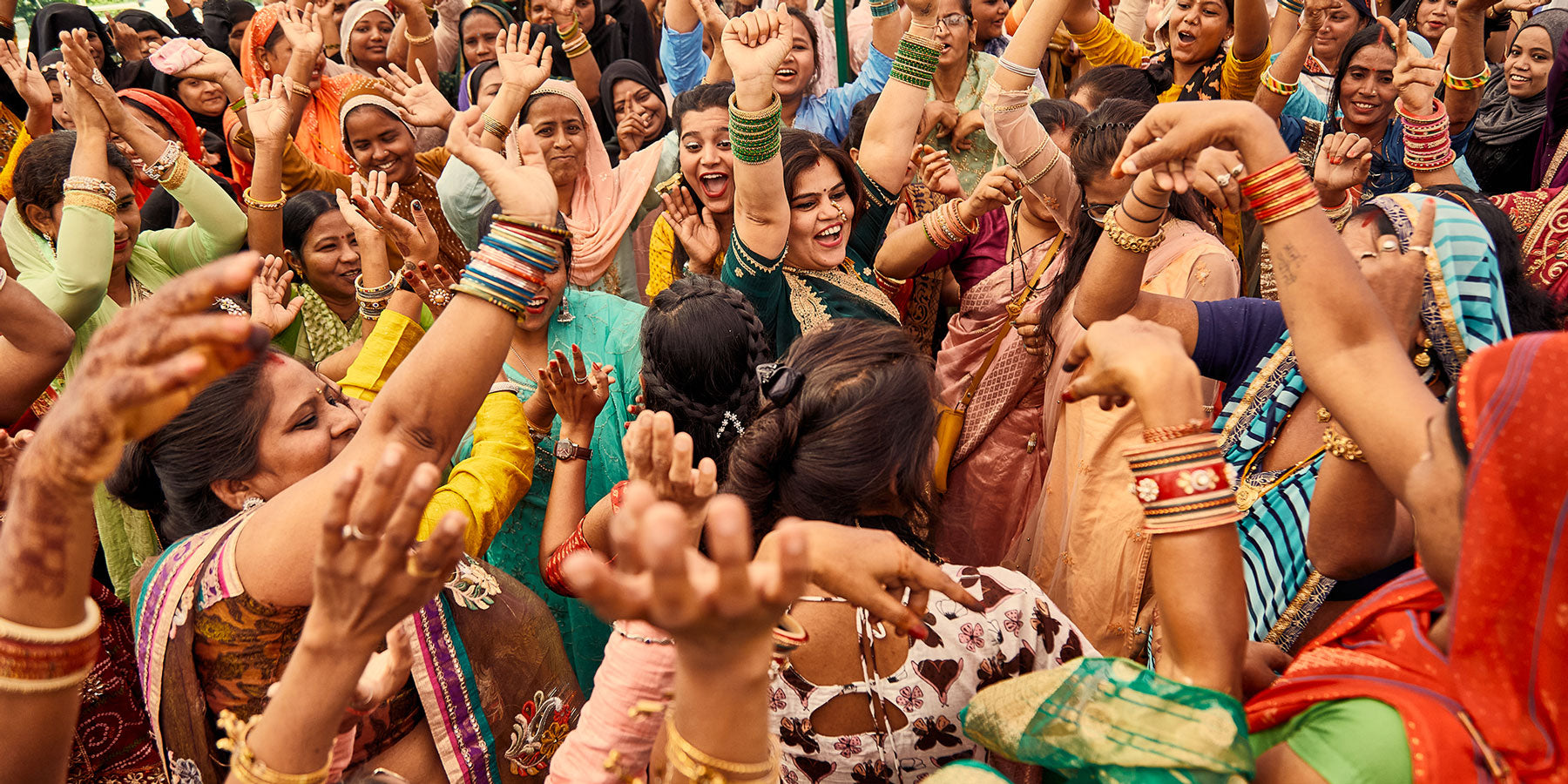 group of women artisans in colorful saris dancing and laughing