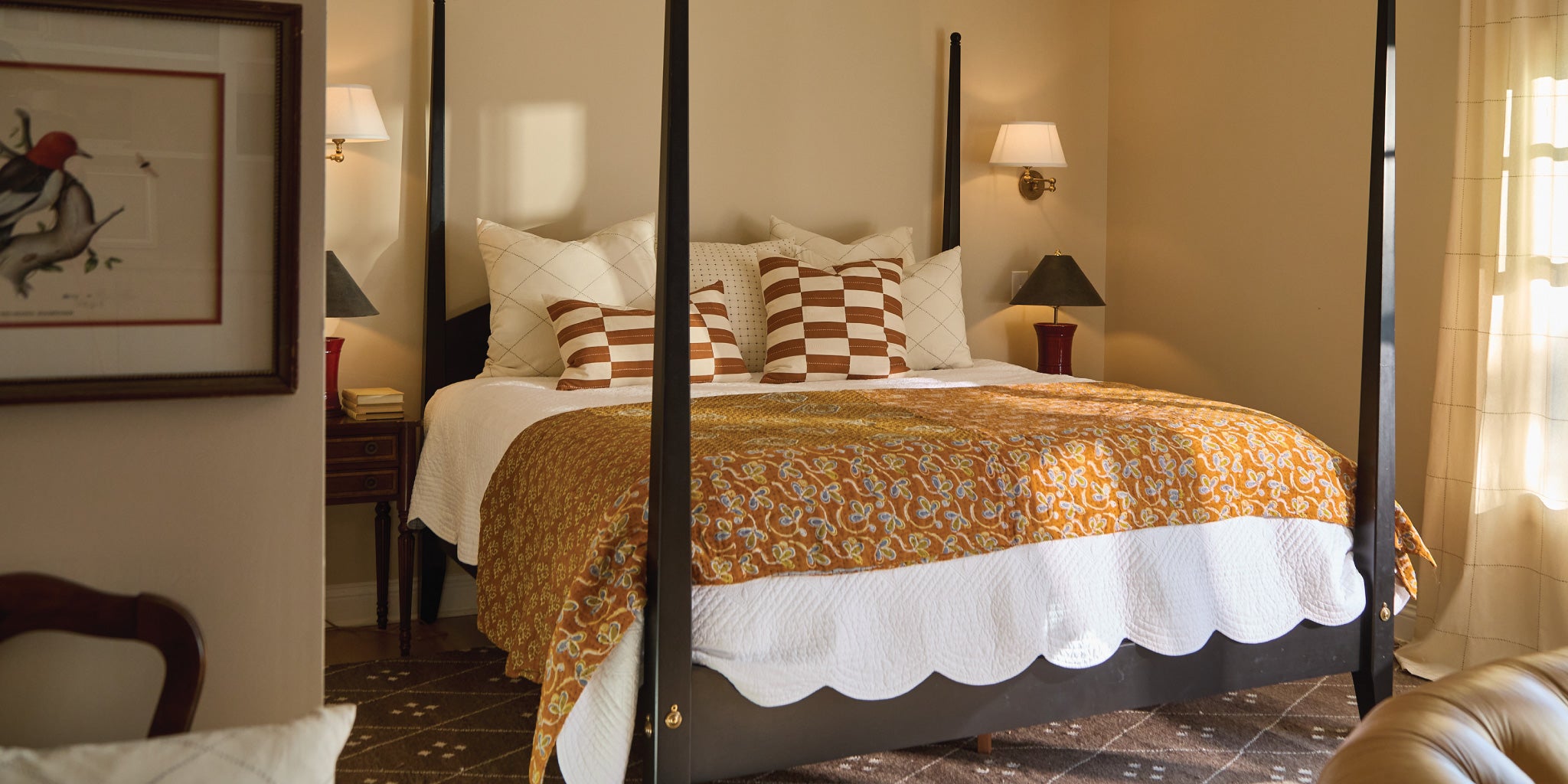 Bedroom with a bed covered in a gold and white patterned comforter, surrounded by furniture and decor.