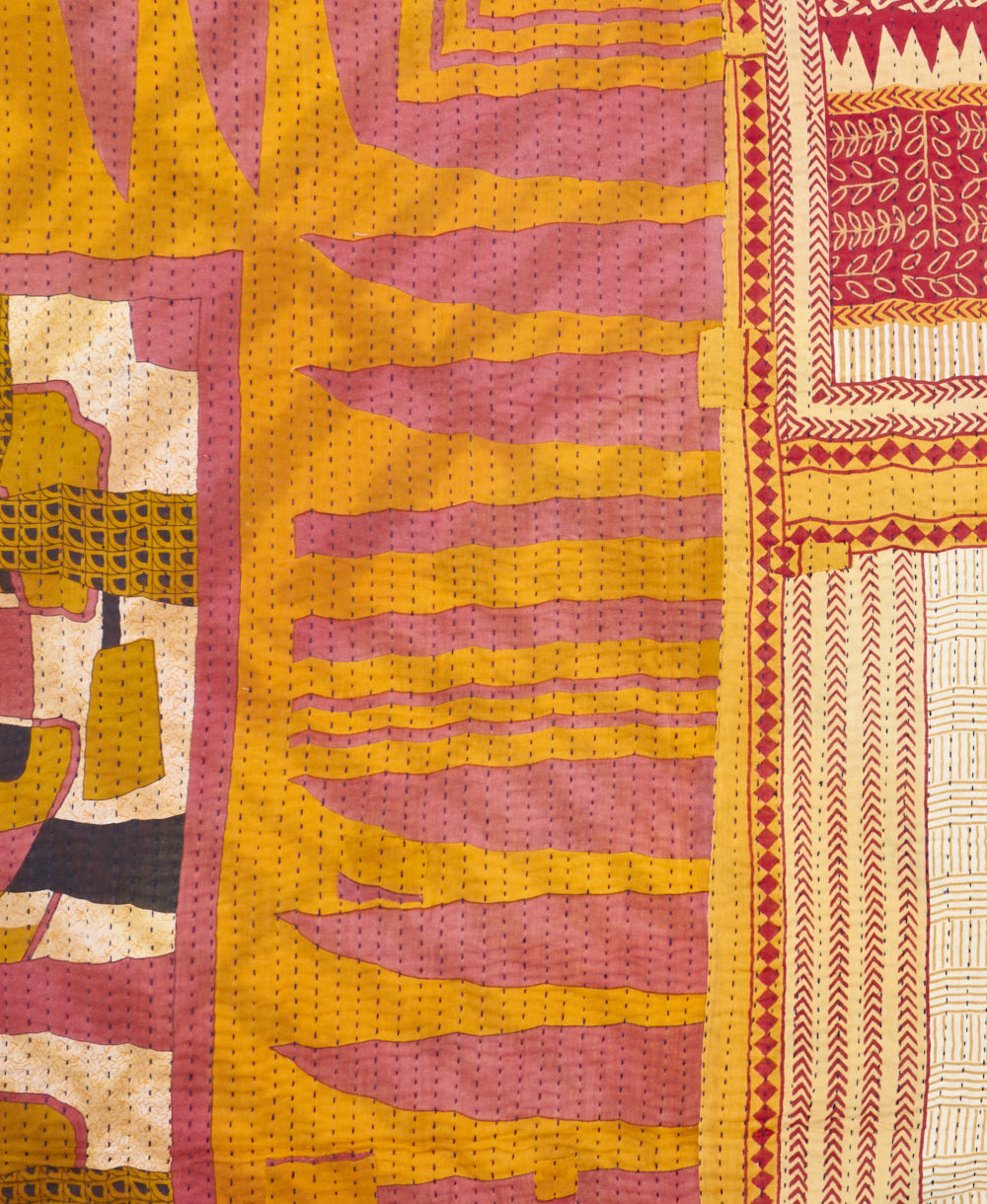 kantha quilt throw with a tag featuring the hand-stitched signature of the maker