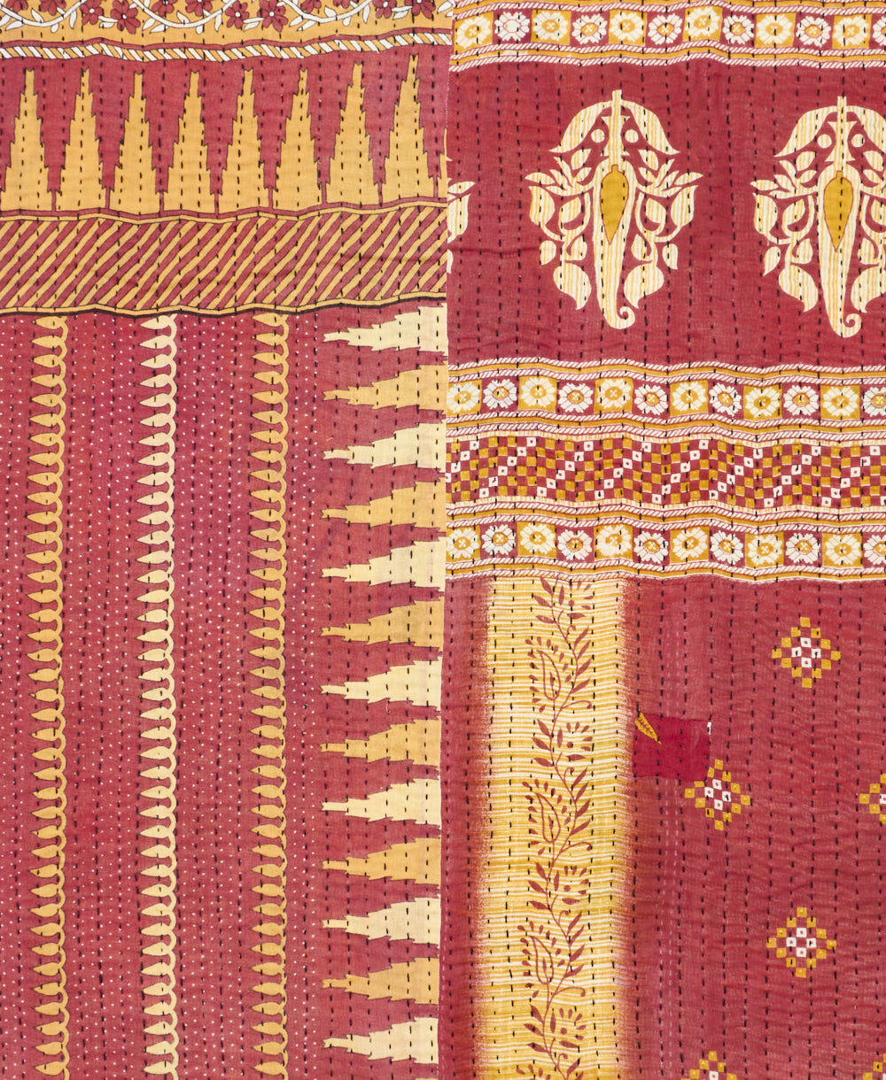 kantha quilt throw with a tag featuring the hand-stitched signature of the maker
