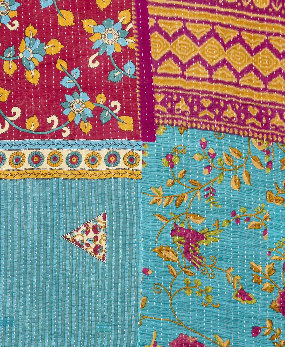 kantha quilt throw with a tag featuring the hand-stitched signature of the maker