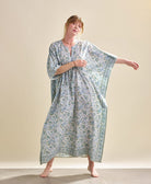 woman wearing organic cotton blue and white floral kaftan with slit neckline and beaded waist tie
