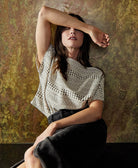 woman wearing a natural white crop top in a structured boxy shape featuring a unique black motif stripe pattern