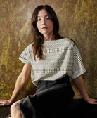 woman wearing a black and white block print crop top with a unique stripe motif pattern paired with a grey denim midi skirt