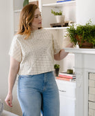 woman wearing white crop top with a bold black geometric embroidery pattern paired with light wash straight leg jeans