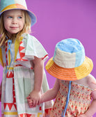 little girls holding hands and wearing colorful bucket hats