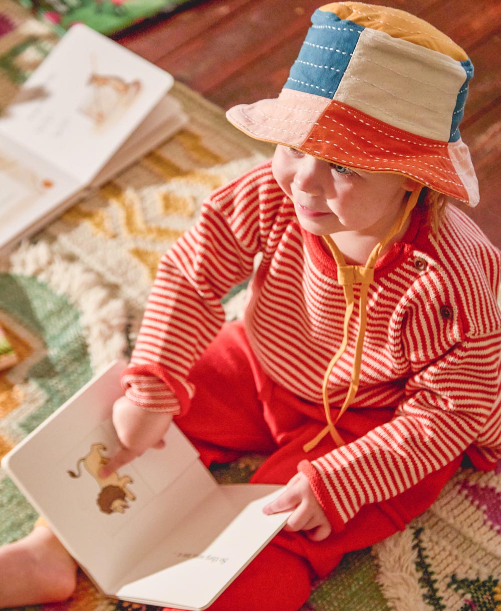 toddler in red and white striped sweater wearing canvas baby bucket hat in rainbow checkered colors