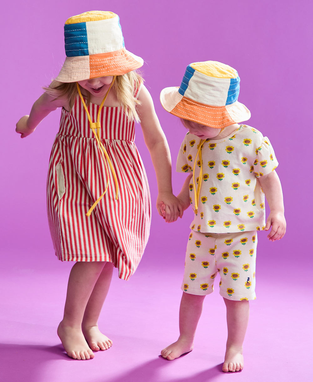 two little girls dancing while wearing checkered bucket hats 