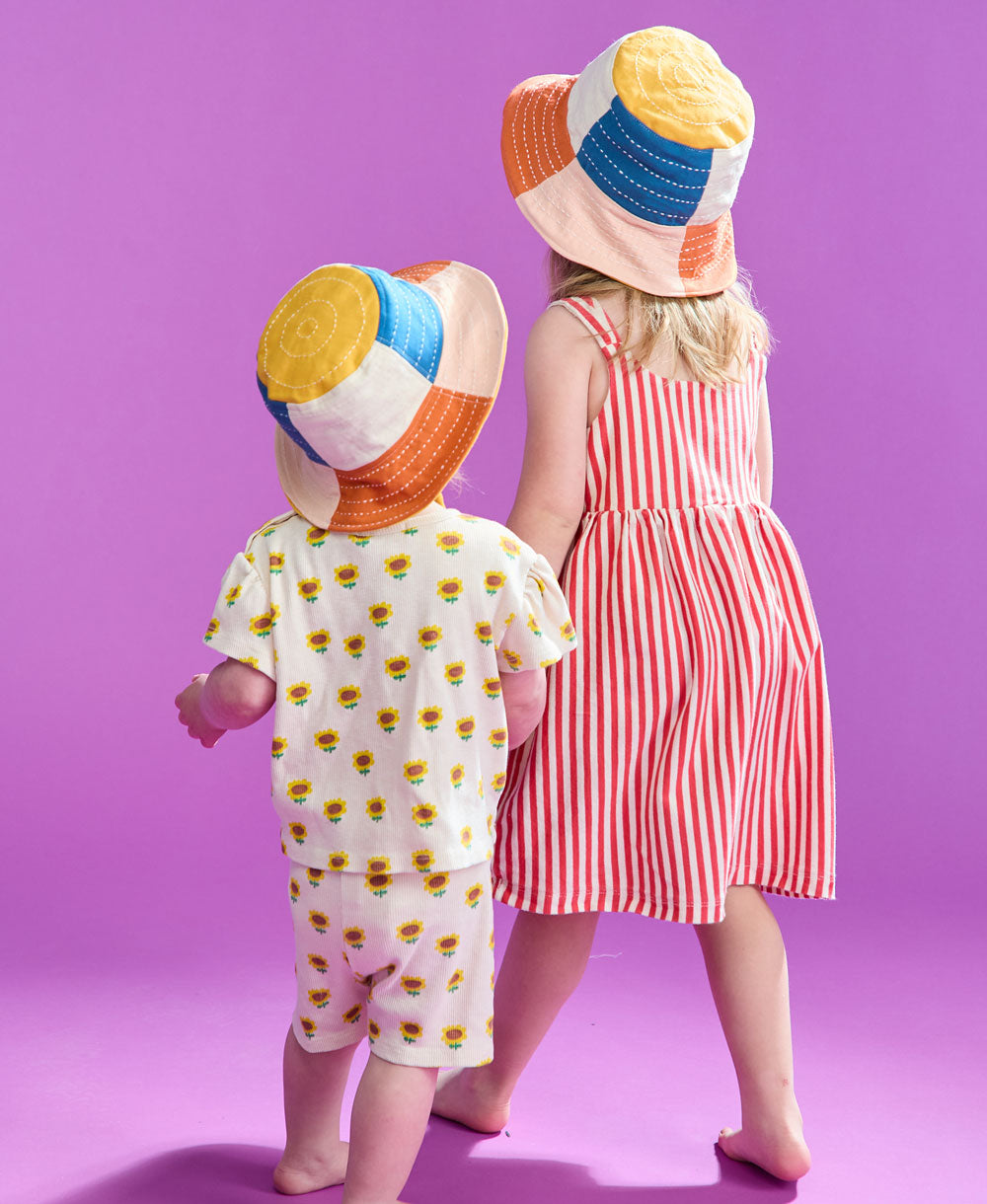 two girls holding hands wearing checkered bucket hats holding hands