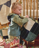 toddler holding fabric basket by handles with blue and green checkered design