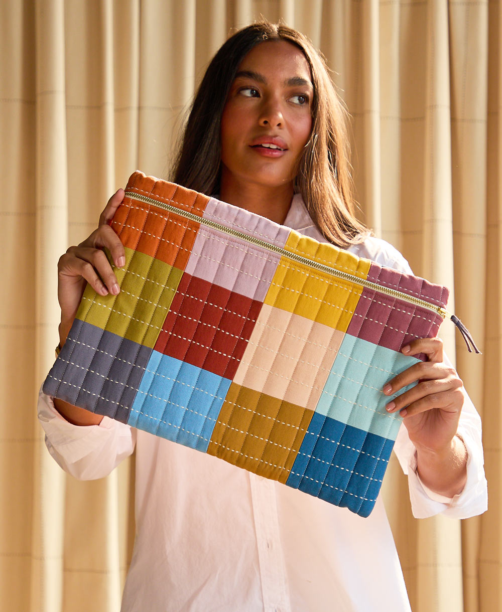 woman holding quilted checkered laptop sleeve in front of her 