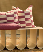 berry checkered pillows sitting on white bench