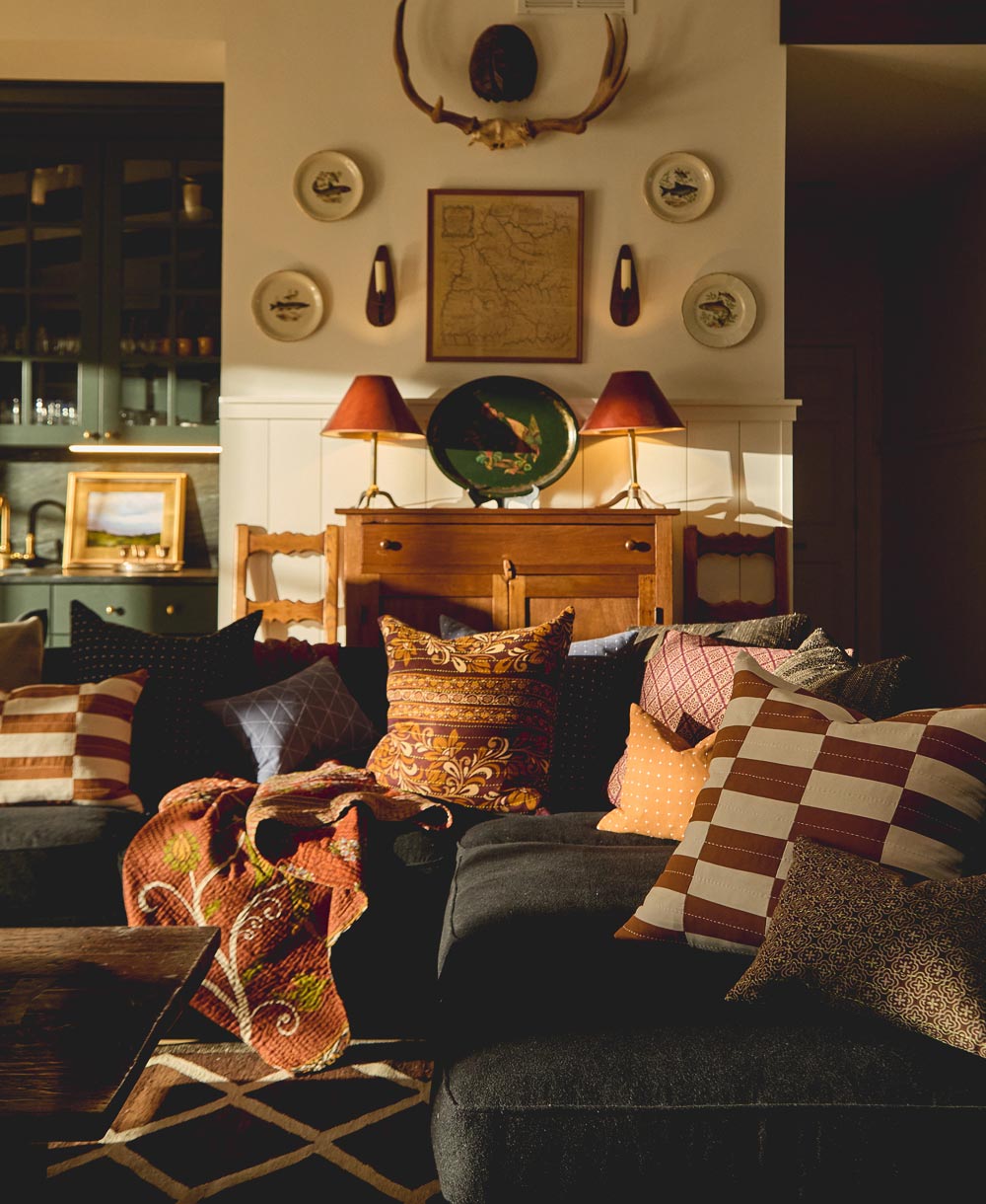 Living room with a wooden cabinet, decorative plates, and patterned modern throw pillows in warm tones