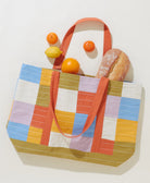 colorful checkered canvas tote bag with orange straps with bread and fruit spilling out for the farmer's market