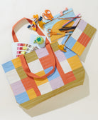 colorful checkered canvas tote with matching pouches holding sewing and embroidery supplies