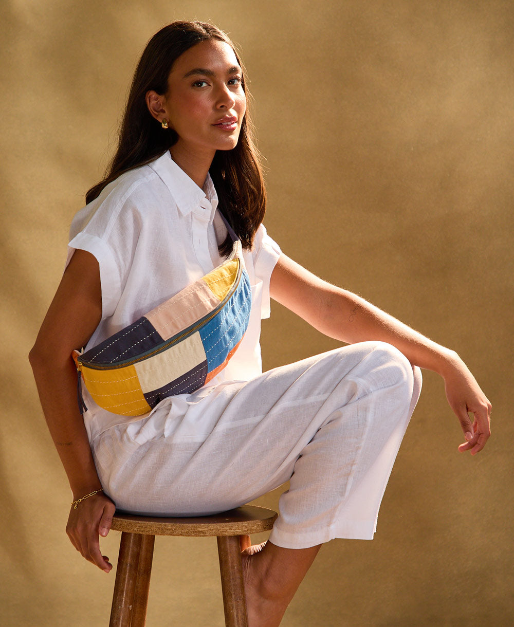 woman sitting on a stool wearing colorblock sling crossbody bag in cobalt