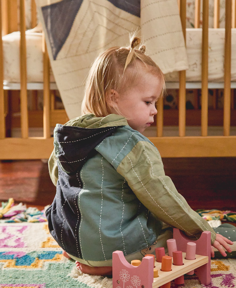 toddler girl wearing sustainably made organic cotton toddler hoodie in blue and green hues