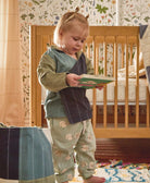 toddler girl wearing colorblock toddler hoodie in sage holding green children's book