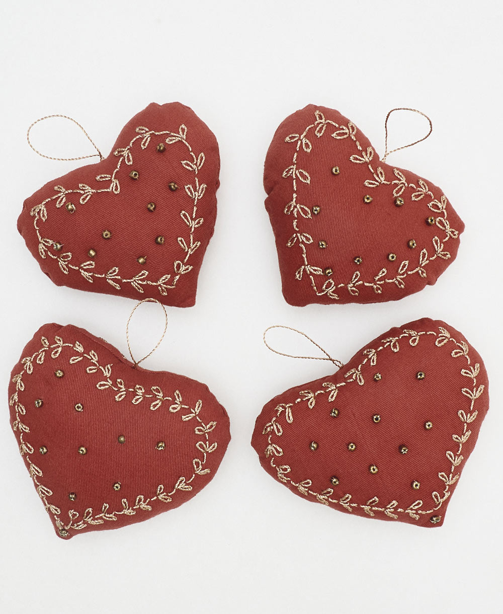 group of rust red handmade heart ornaments with gold stitching and gold beads