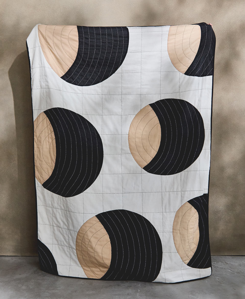 crescent lattice patchwork quilt with bold graphic circular design in tan and black