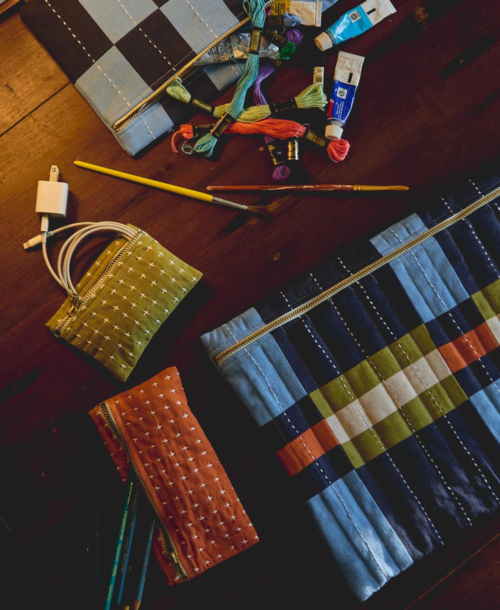 cross-stitch coin purses on wooden table with other checkered colorful pouches