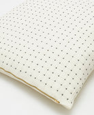 ivory euro sham with tiny black embroidered cross-stitches across the front & gold zipper closure