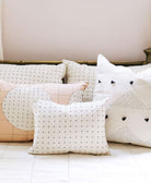 cross-stitch small pillow on all white bed with other matching pillows in front of vintage brass headboard