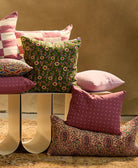 berry small cross stitch pillow with other colorful pillows on a white bench