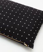 black small pillow with tiny white embroidered cross-stitches & gold metal zipper