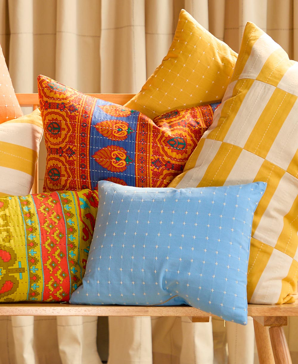blue cross stitch pillow on bench 