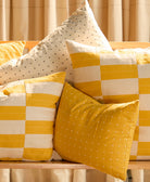 mustard small pillow on bench with white and mustard checkered pillows